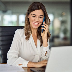 Woman smiling while talking on phone in office