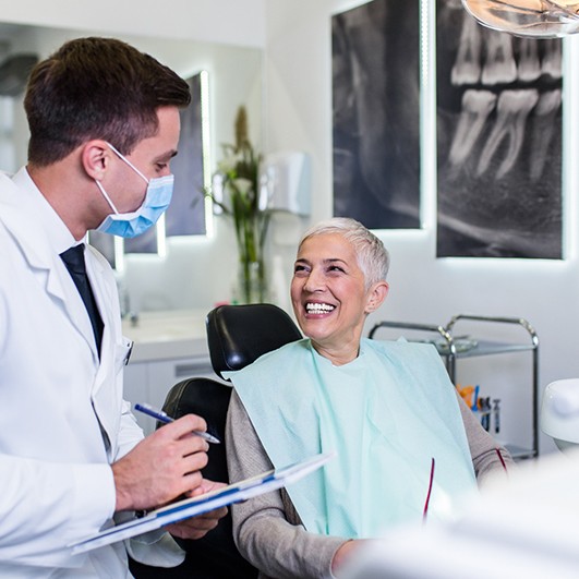 Dentist with clipboard talking to smiling patient