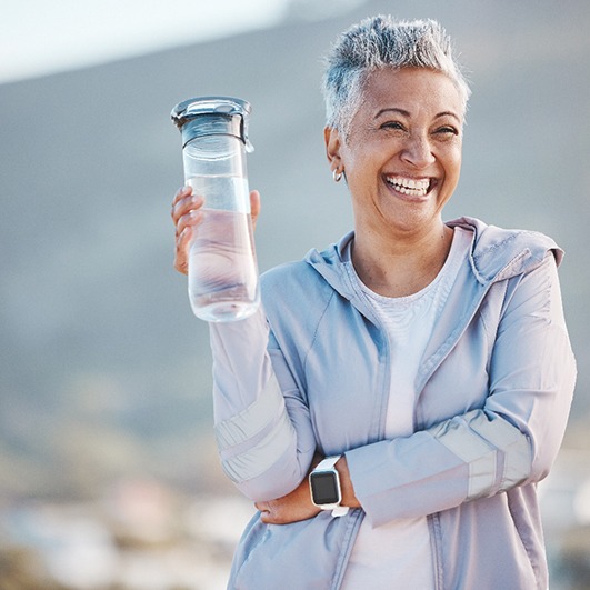 Woman smiling with water bottle on hike outside