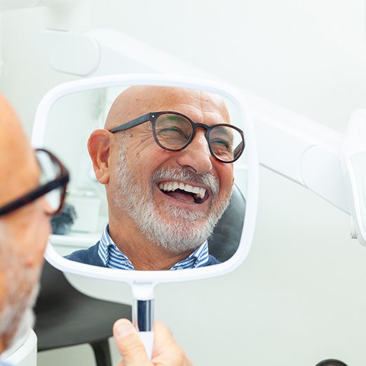 Man with glasses smiling in reflection in mirror