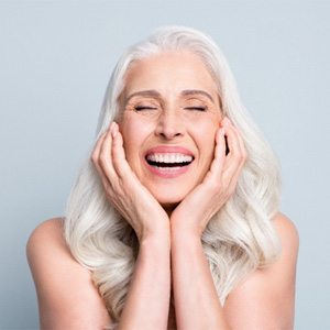 Woman with long gray hair smiling with eyes closed