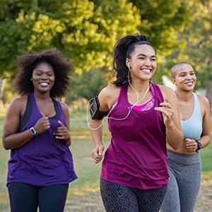 Friends smiling while jogging together in park
