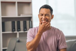 Man clenching mouth in pain.